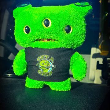 Volt, a small green plush toy that rides on the van dashboard